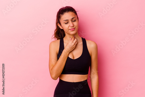 Fototapeta Naklejka Na Ścianę i Meble -  Young sport Indian woman isolated on pink background suffers pain in throat due a virus or infection.