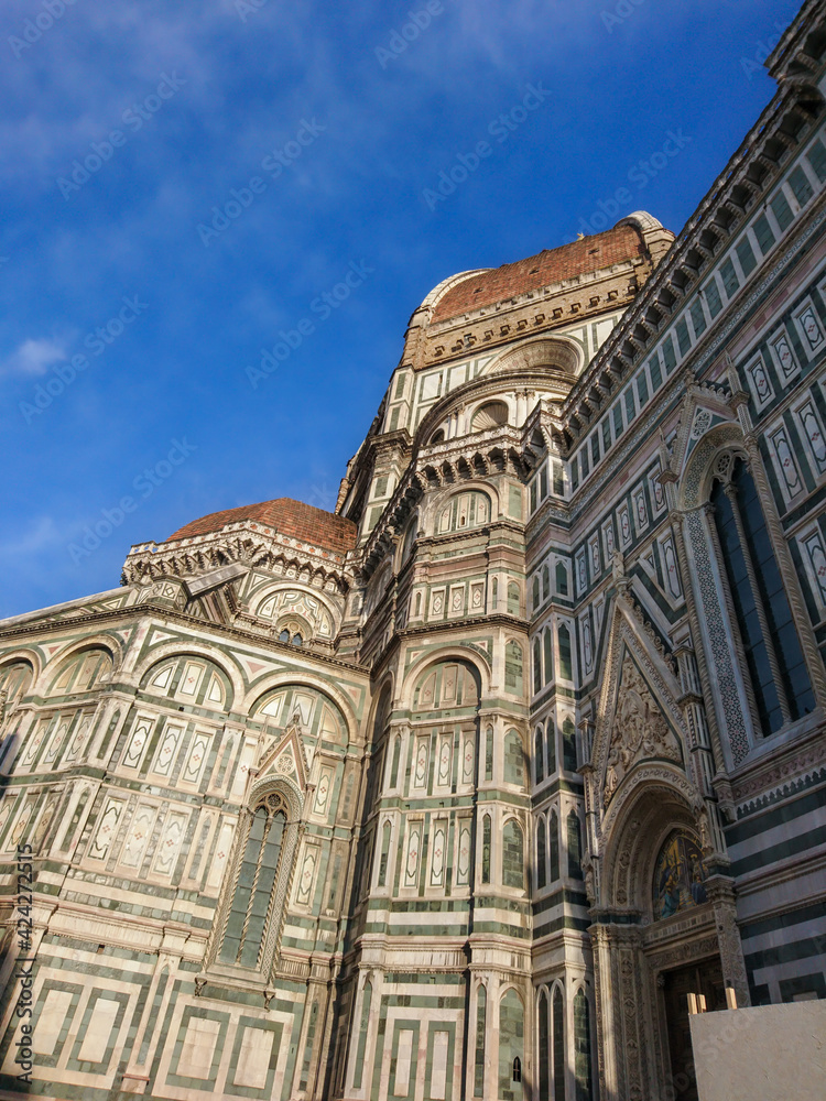 Cathedral of Santa Maria del Fiore. Landmark 1200s cathedral colored marble side facade sunny view with blue sky background. Travel Italy