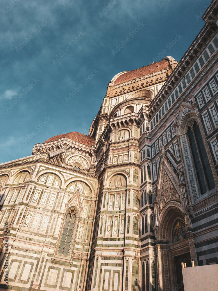 Cathedral of Santa Maria del Fiore. Landmark 1200s cathedral colored marble side facade sunny view with blue sky background. Travel Italy. Color graded