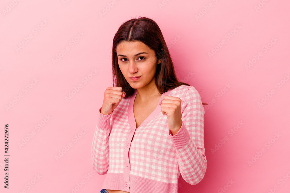 Young Indian woman isolated on pink background showing fist to camera, aggressive facial expression. Young Indian woman isolated on pink background showing fist to camera, aggressive facial expression.