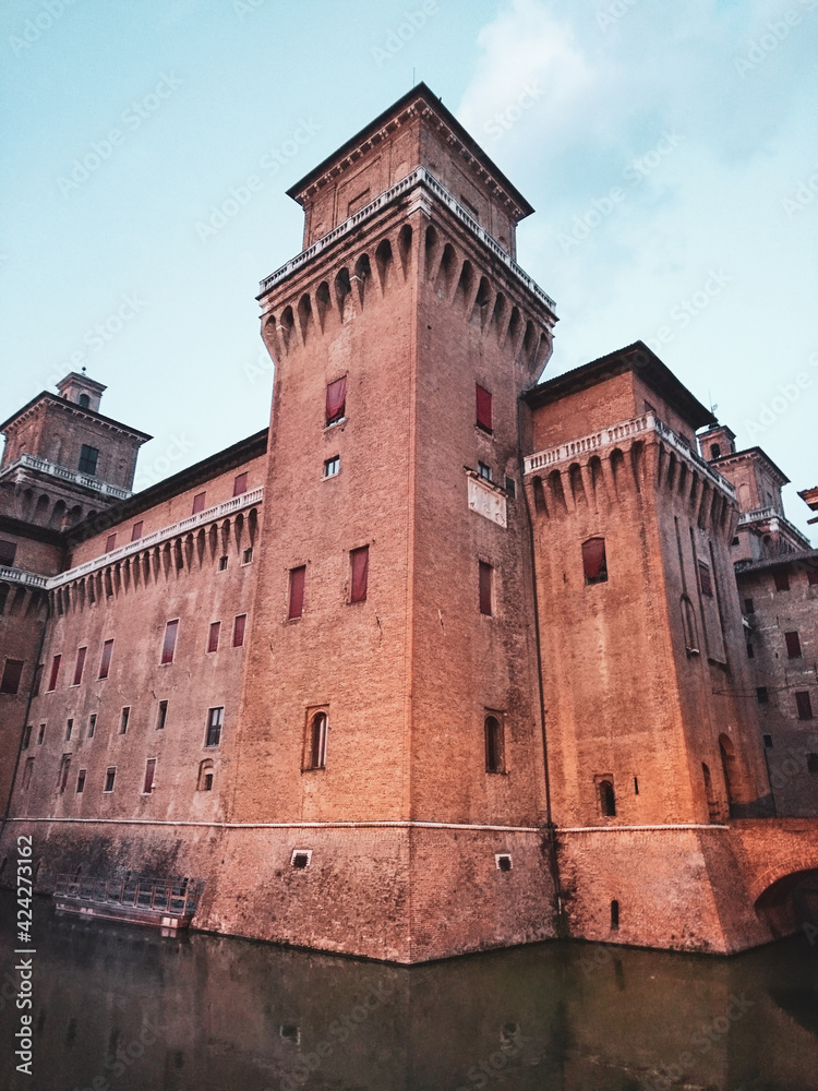 Corner tower of Castello Estense di Ferrara (Este castle) or castello di San Michele (St. Michael's castle) a moated red brick medieval castle on water in center of Ferrara, northern Italy