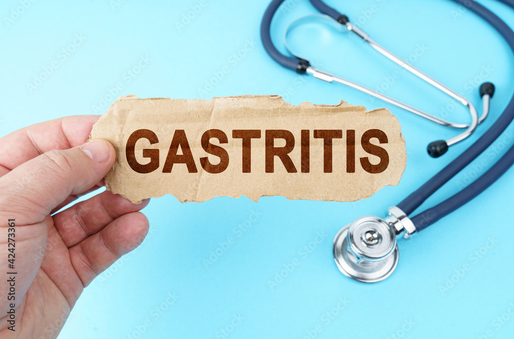 On a blue background, a man holds a cardboard box with the inscription - GASTRITIS On a blue background, a man holds a cardboard box with the inscription - GASTRITIS