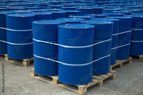There are many round barrels in white and blue at the production site. The barrels contain oil and chemical products.