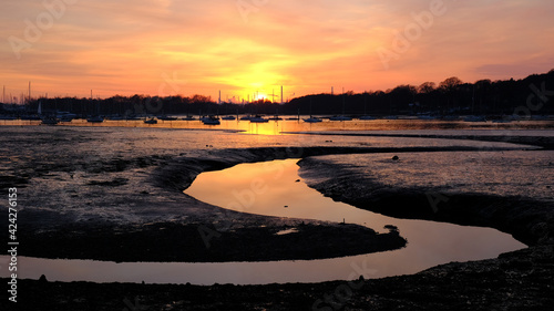 An estuary at sunset with the sun reflecting in the river.