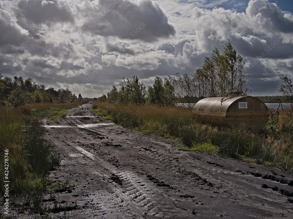 Wassertank für Löschwasser am Rande eines breiten Moorwegs mit Reifenspuren