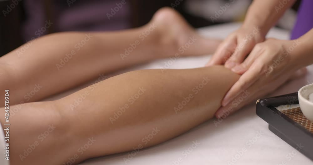 Woman relaxing and getting massage on legs by female therapist. Partial view professional treatment in wellness spa. Concept of body care. Slow motion. Woman relaxing and getting massage on legs by female therapist. Partial view professional treatment in wellness spa. Concept of body care. Slow motion.