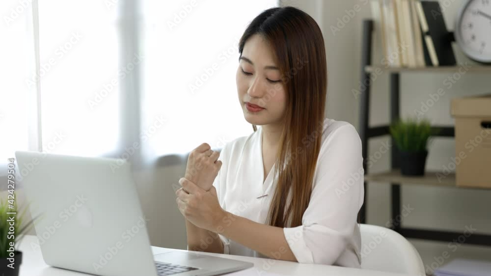 Young asian woman texting on keyboard laptop work so hard and long time that he has office syndrome. She has wrist pain, from working with laptop sitting in office Young asian woman texting on keyboard laptop work so hard and long time that he has office syndrome. She has wrist pain, from working with laptop sitting in office