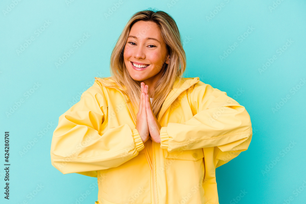 Young mixed race woman isolated on blue background holding hands in pray near mouth, feels confident.
