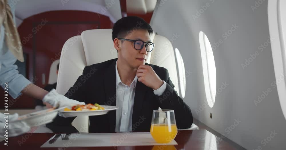 Flight attendant serving food for asian businessman flying first class