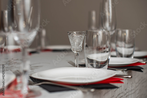 Empty glasses and plate set in restaurant. Red and black napkins.