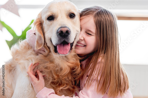 Canvas Print Little girl petting golden retriever dog