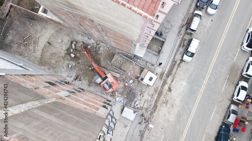 Aerial view of excavation work at the city center. Excavator is filling the land into the truck between buildings. 