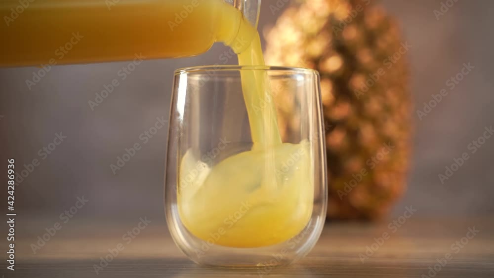 Pineapple fruit and juice in double glass cup. Pouring tropical juice into glass. Pineapple fruit and juice in double glass cup. Pouring tropical juice into glass.