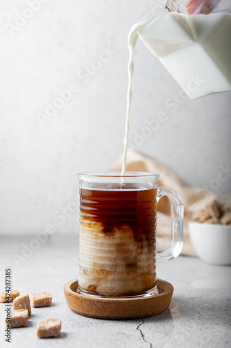 cold drink with coffee and milk. glass transparent mug, on a light background. vertical position