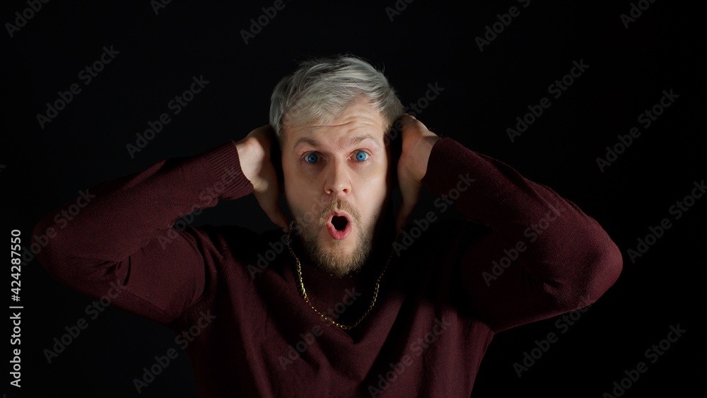 Shocked amazed handsome man in stylish blouse feeling excitement, looking at camera and holding hands near face on black background. Facial expression of trendy bearded guy surprised say wow omg Shocked amazed handsome man in stylish blouse feeling excitement, looking at camera and holding hands near face on black background. Facial expression of trendy bearded guy surprised say wow omg