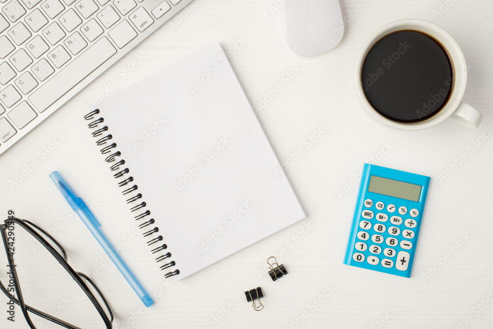 Top view photo of business workplace with keyboard mouse cup of coffee binders glasses notebook with copyspace blue calculator and pen on isolated white background Top view photo of business workplace with keyboard mouse cup of coffee binders glasses notebook with copyspace blue calculator and pen on isolated white background