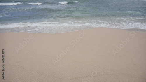 Beach waves foaming on white sand