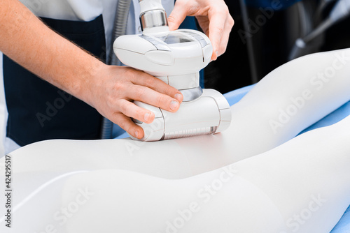 Vacuum roller massager in the hands of a doctor body close up.
