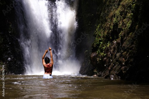 Medium shot of a beautiful woman of latin american ethnicy standing in front of a large waterfall photo