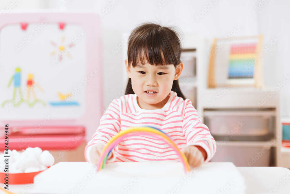 young girl making rainbow craft using pipe cleaner at home
