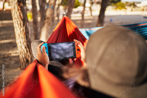 Unrecognizable man playing games on hammock. Chill and gaming concept.