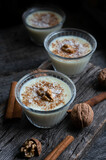 Pudding in glass bowl with cinnamon and walnut on rustic table, milk dessert