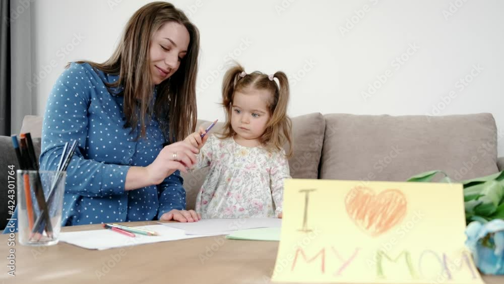Little girl with pregnant mother drawing a picture at home