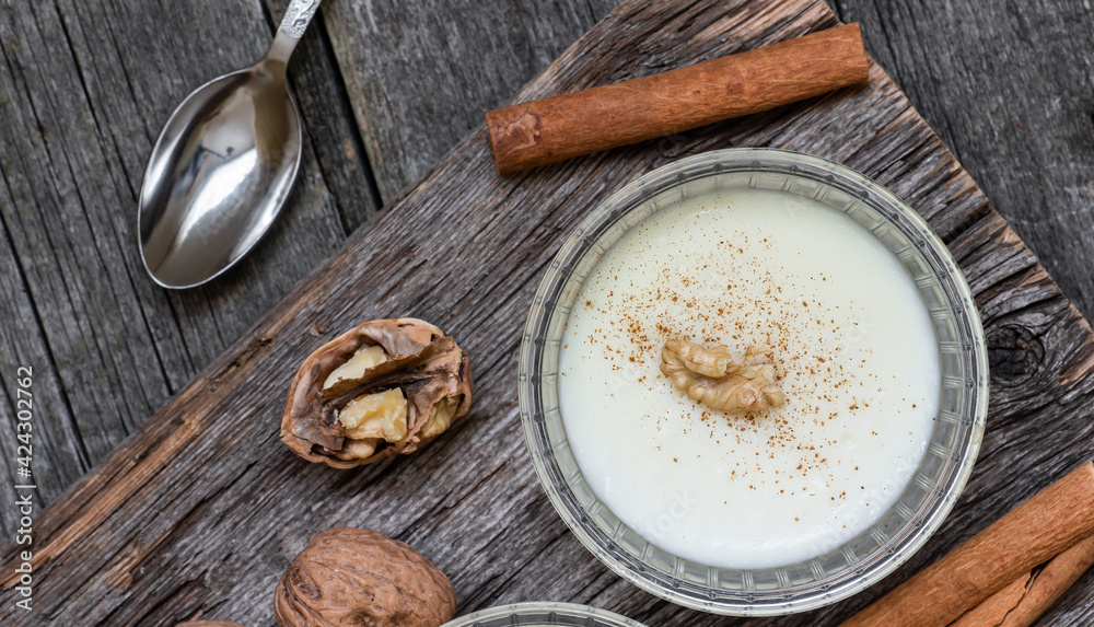 Pudding in glass bowl with cinnamon and walnut on rustic table, milk dessert Pudding in glass bowl with cinnamon and walnut on rustic table, milk dessert