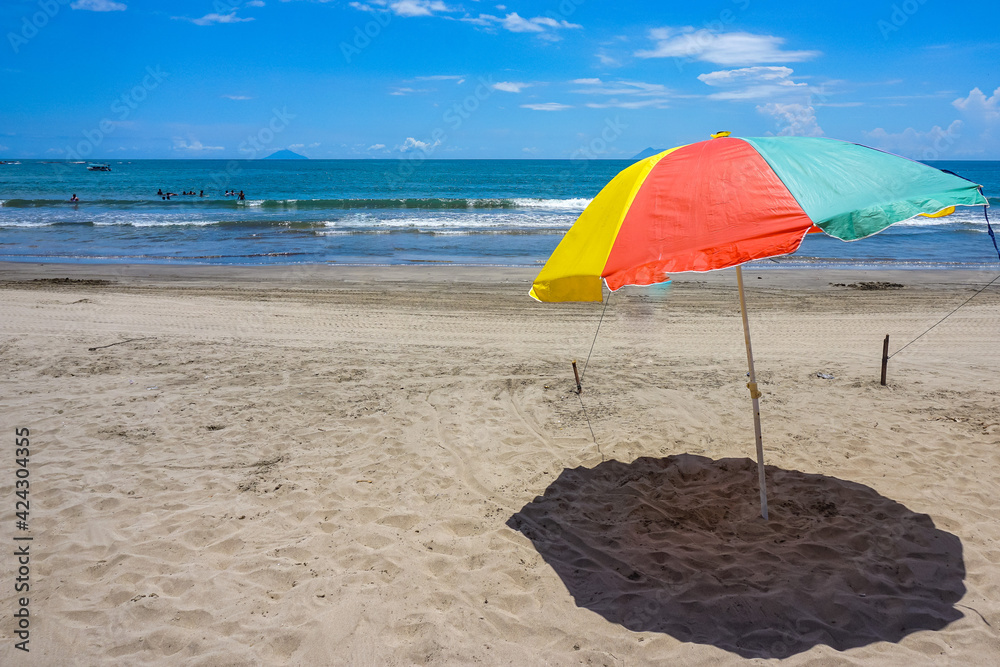 Colorful umbrella on the sand beach under blue sky. Summer vacation and traveling destination. 
