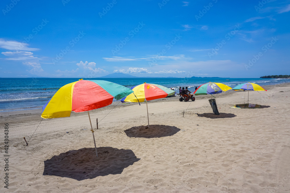 Colorful umbrella on the sand beach under blue sky. Summer vacation and traveling destination. 