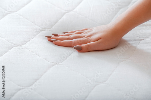 Female hand Pressing Testing mattress to Check softness. Choice comfortable mattress for sleep in store. quality control hardness of mattress materials Orthopedic Foam. Woman choosing new mattress.