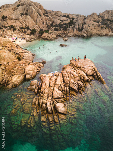 Aerial view of a few people relaxing on the rocks near a small paradise beach in Cala Coticcio, Caprera, La Maddalena, Sardinia, Italy. photo