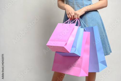 Young happy summer shopping woman with shopping bags isolated on grey background