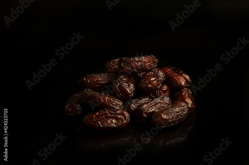 Dates on a black background. Dried fruits. Dried dates lie next to each other	
