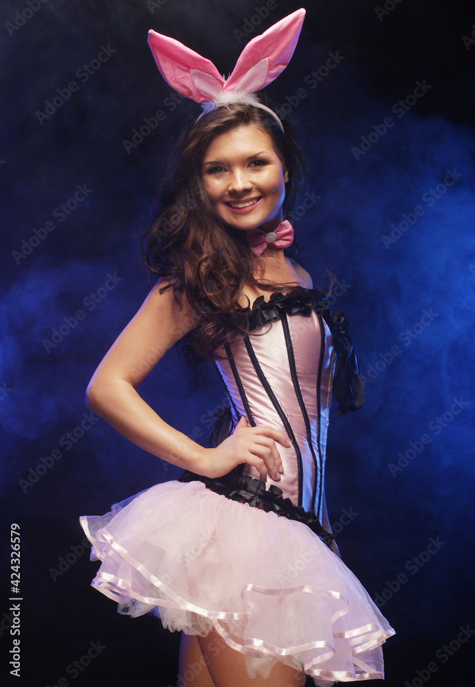 Sexy young brunette female in bunny costume over dark background. Stock