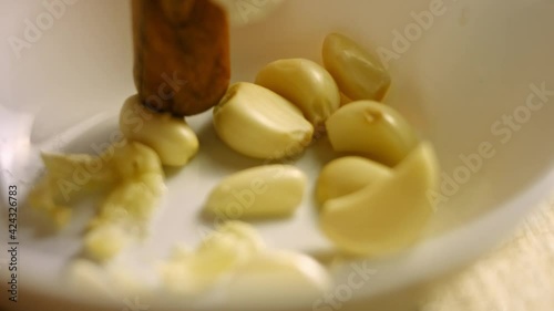 Female hands in gloves pressing peeled cloves in a bowl. Process of cooking shkmeruli - Georgian dish. Macro view photo