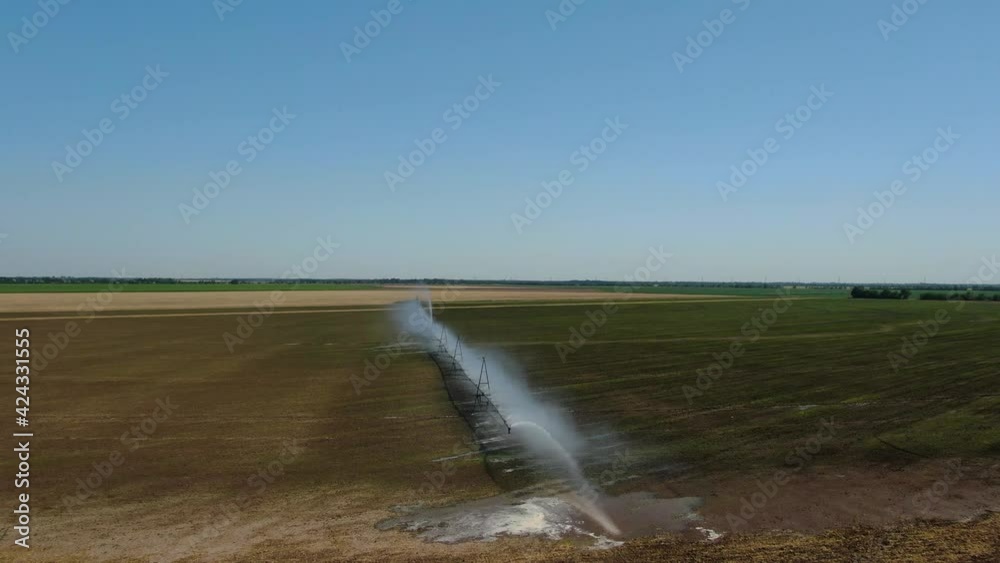 Irrigation system on agricultural land. A large stream of water to irrigate the field. Watering the field, top view. Channel for watering the fields. Rainbow on water. Irrigation system on agricultural land. A large stream of water to irrigate the field. Watering the field, top view. Channel for watering the fields. Rainbow on water.