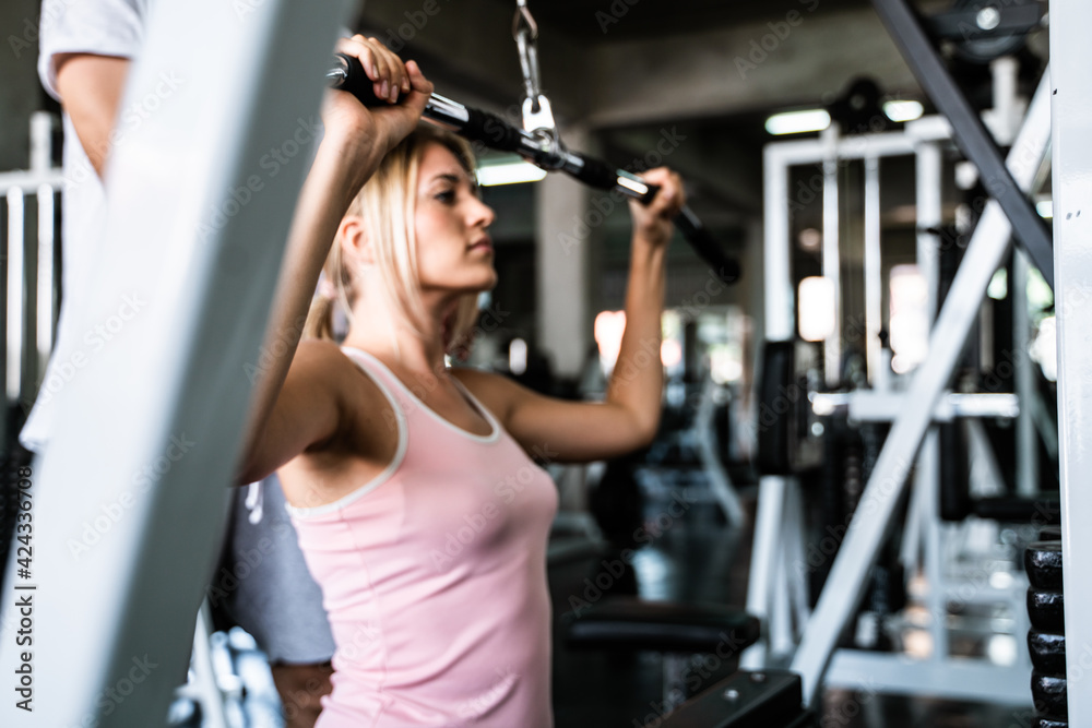 Smart sport women lift up barbell with trainer man in gym Smart sport women lift up barbell with trainer man in gym
