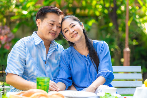 Senior retirement couple sitting in park on wood bench talking together