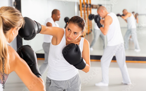 Two diligent efficient women in boxing gloves have boxing fight in the gym