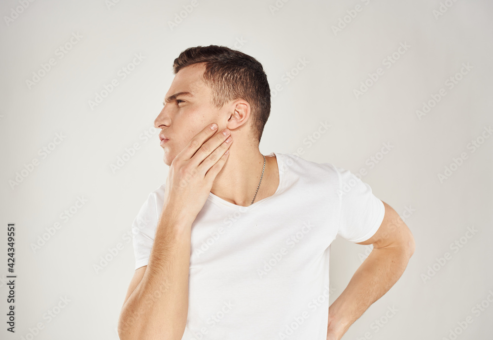 Portrait of a pensive man in a white T-shirt side view light background Portrait of a pensive man in a white T-shirt side view light background