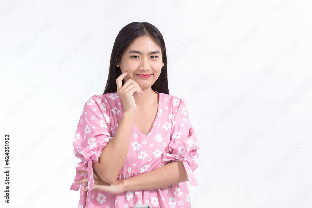 Asian woman smiles with fresh face and wears pink dress while touch her face on white background. Asian woman smiles with fresh face and wears pink dress while touch her face on white background.