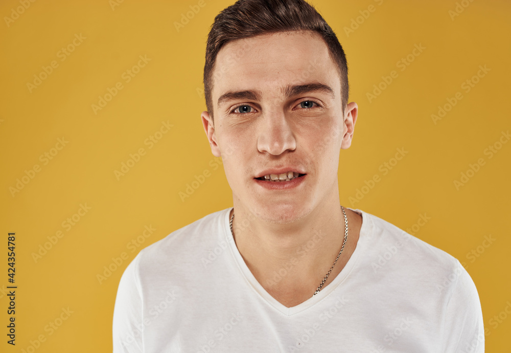 Portrait of a young man in a white T-shirt on a yellow background close-up model