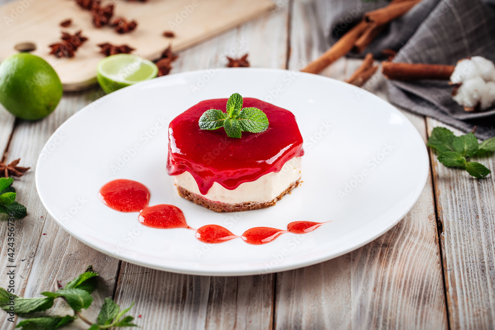 Side view on berry cheesecake with mint on a white plate