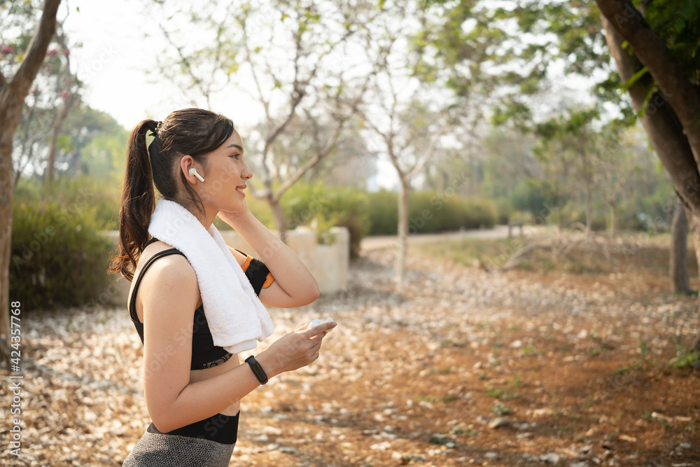She view of healthy young woman in sportswear wearing earphone before running in the park. She view of healthy young woman in sportswear wearing earphone before running in the park.