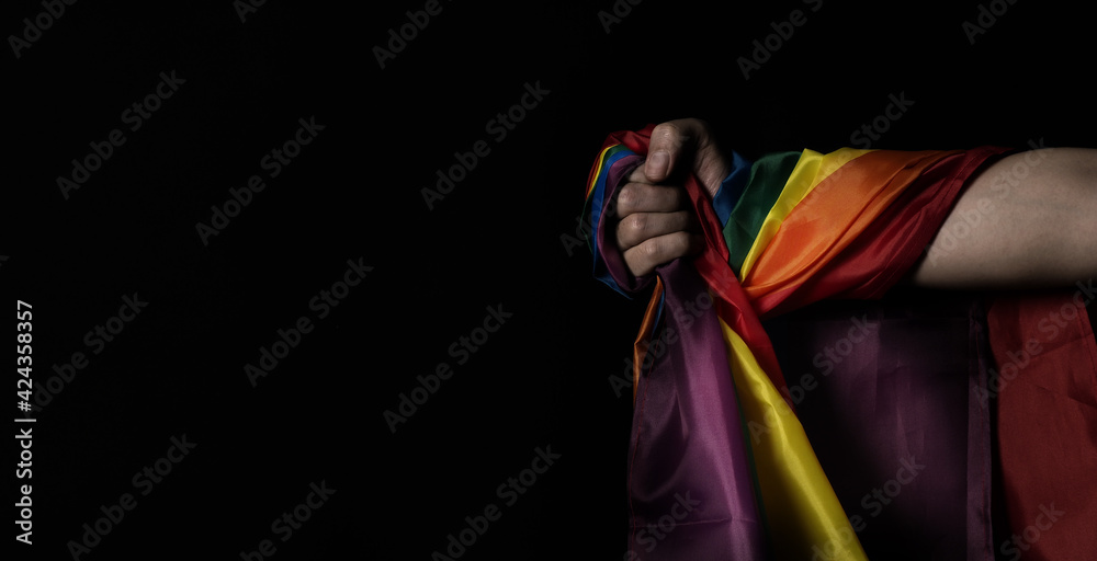 Flag of pride. LGBTQ flag and hand. Lesbian Gay Bi sexsual Transgender Queer or homosexsual pride Rainbow flag. black background. Represent hand symbol of freedom equality.