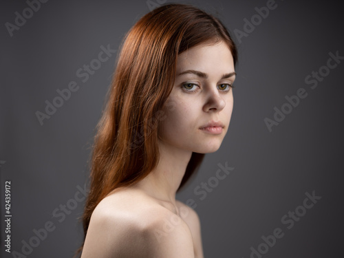 Woman model close-up naked shoulders red hair dark background