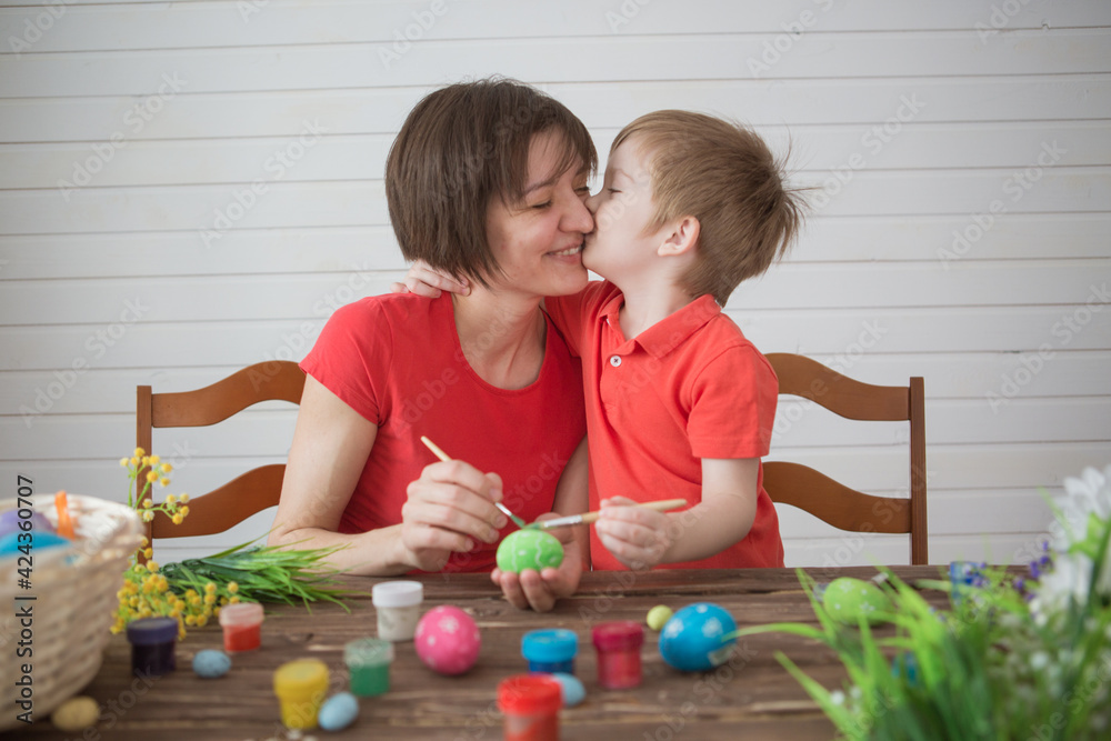 Obraz premium Mother and her son painting Easter eggs. Happy family preparing for Easter day