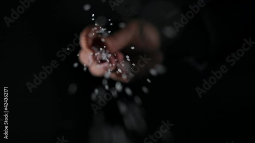 Person sprinkling salt. Chef sprinkles salt crystals over camera. black background, slow motion, close up
