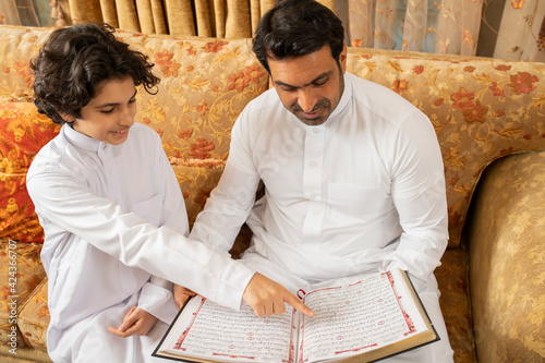 Arabian Father and Son reading Quran Holy Book photo